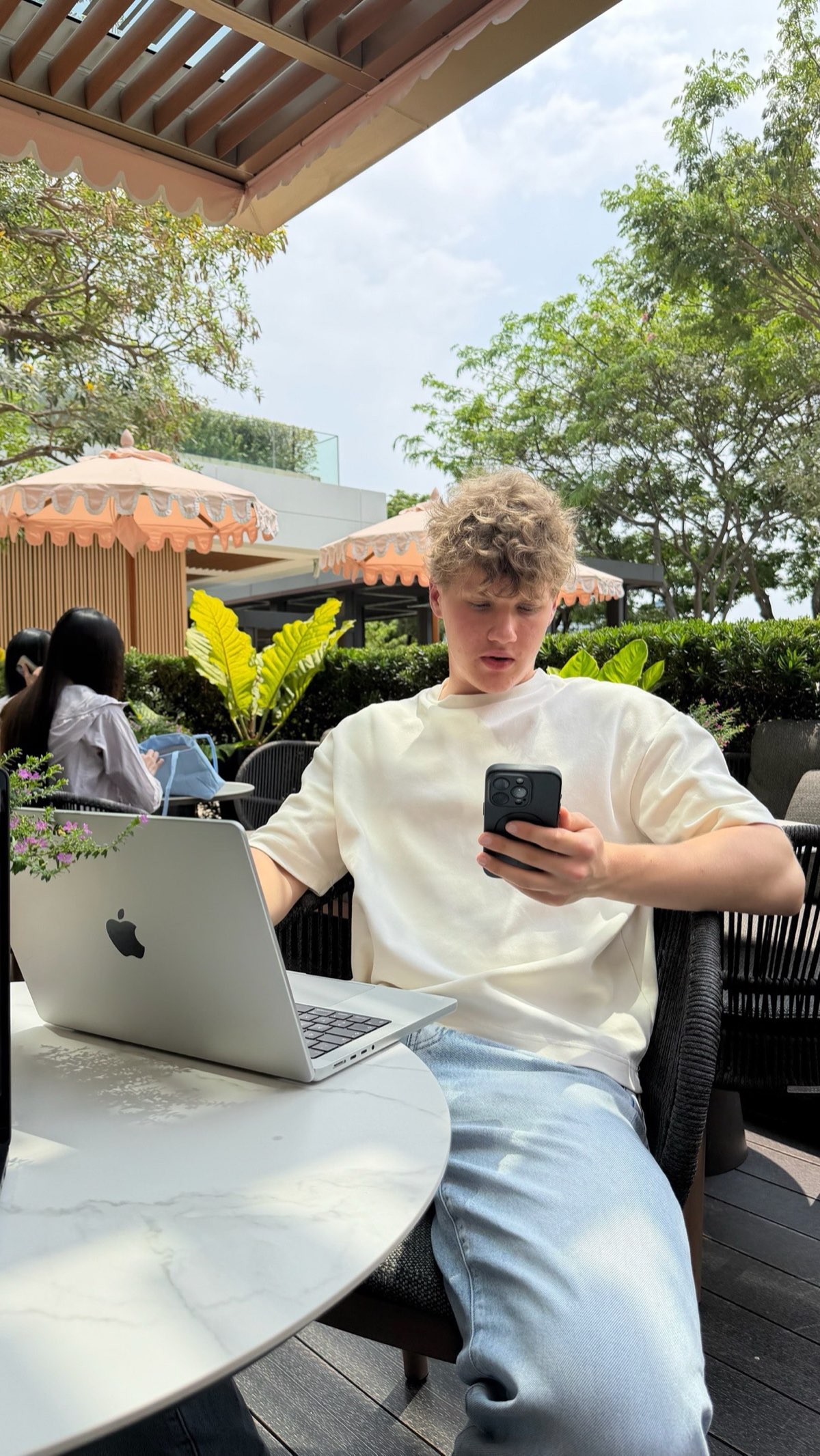 Peer at a cafe, phone in hand, scrolling content.