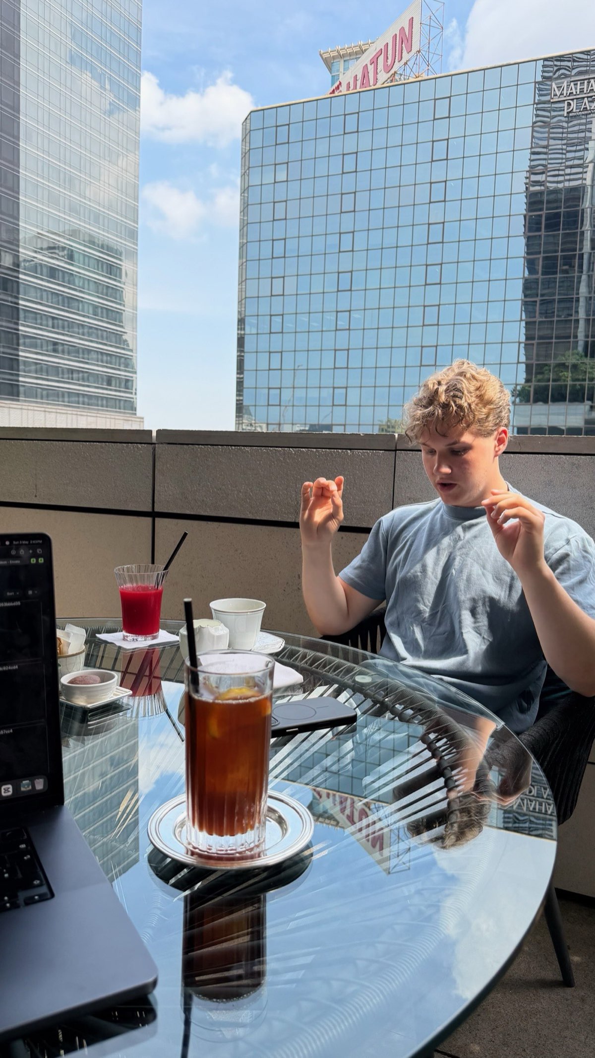Peer mid-conversation on a Bangkok rooftop cafe.