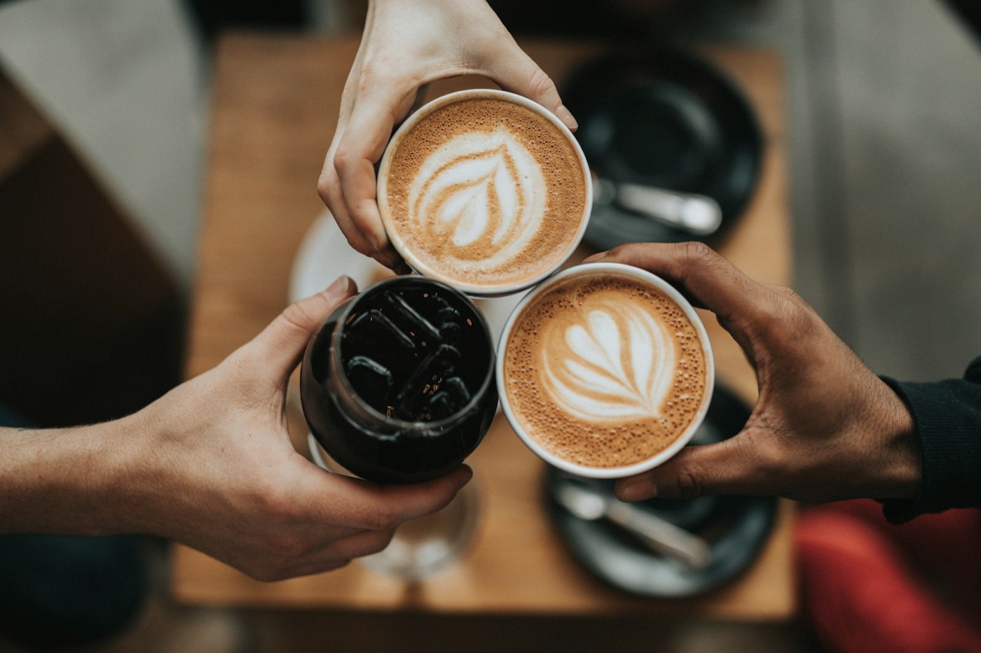 Three hands meeting over coffee cups.